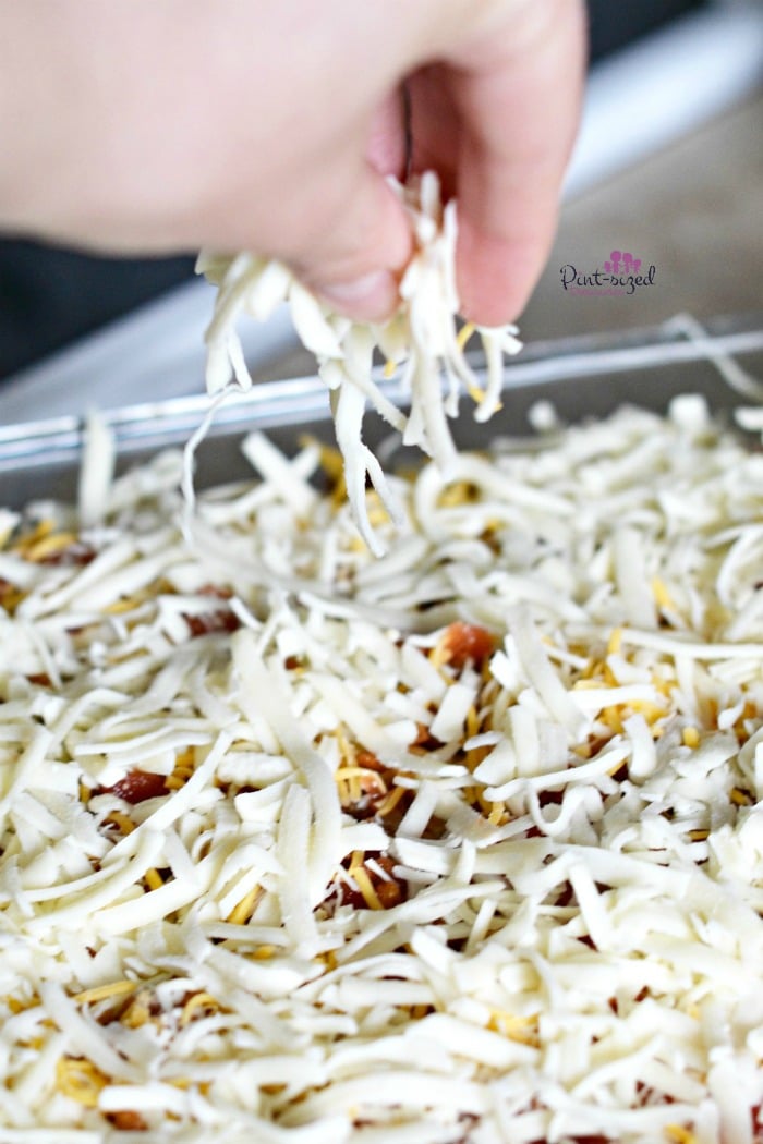 Creating the easy taco bake with layers of shredded cheese.