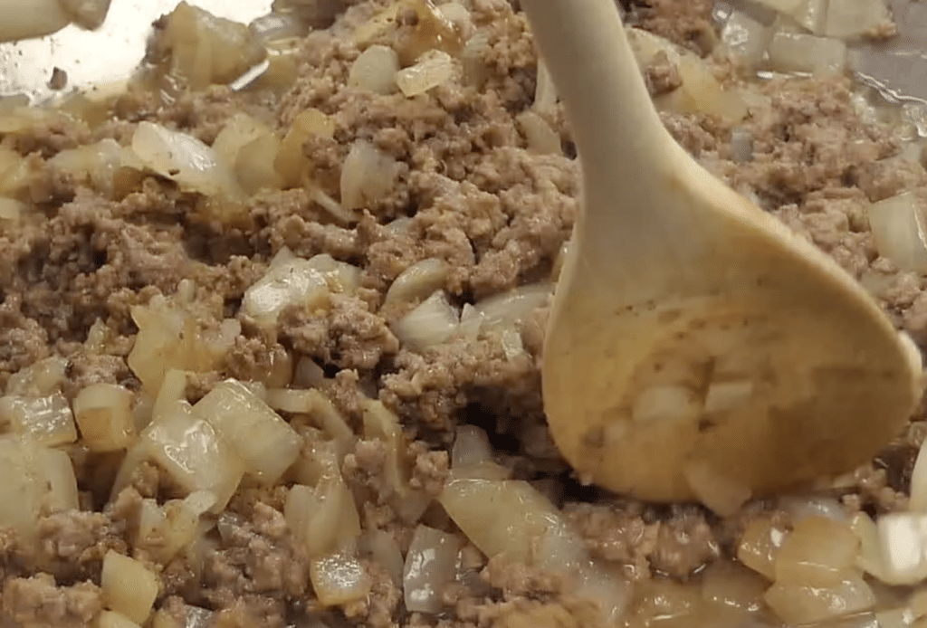 stirring ground beef mixture for tater tot casserole