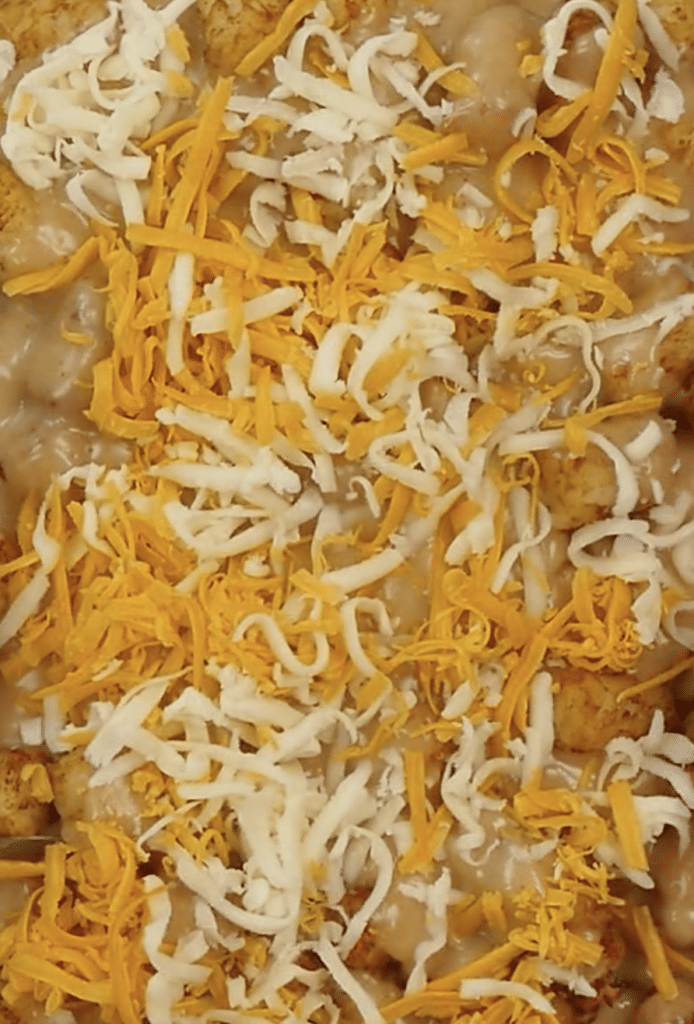 pouring cheese over tater tot casserole