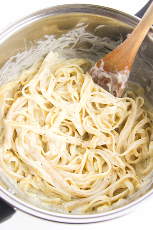 stirring the Alfredo Sauce into the noodles