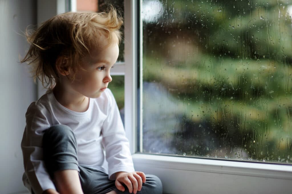cranky toddler sitting by window