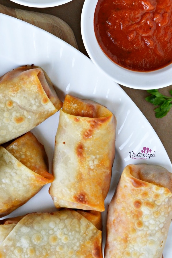 pizza egg rolls with dipping sauces on tray