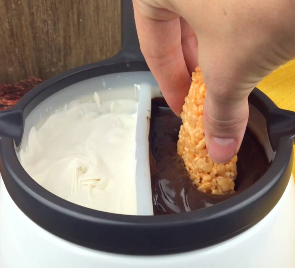 dipping the candy corn treats into chocolate