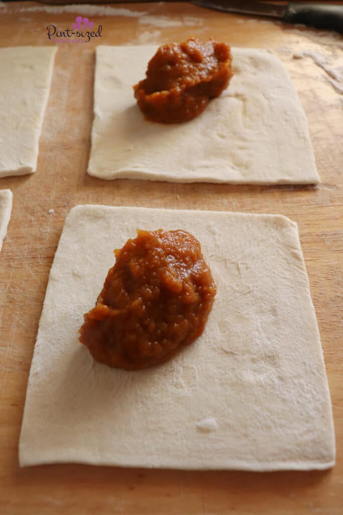 putting filling for pumpkin turnovers onto pastry