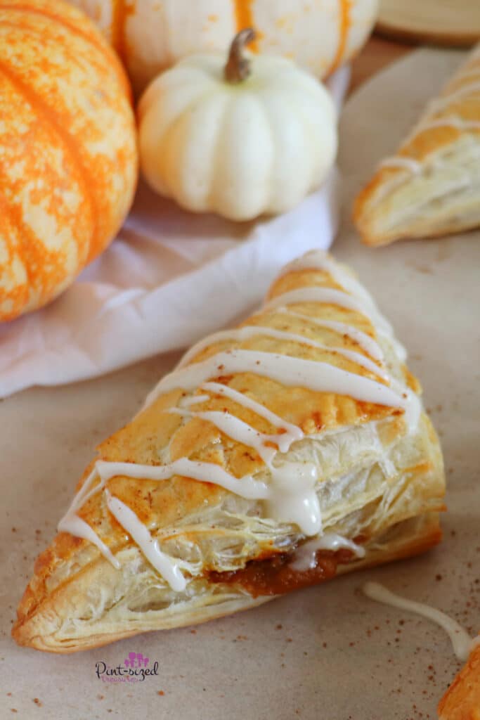 pumpkin turnovers on white parchment paper with sprinkles of cinnamon