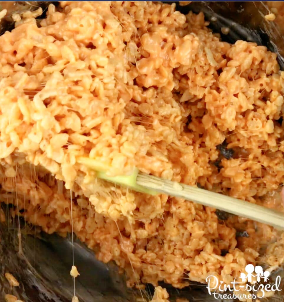stirring rice krispy cereal and marshmallows together for candy corn treats