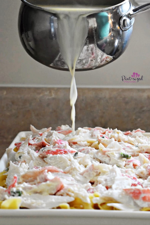 pouring sauce over noodles for crab rangoon casserole