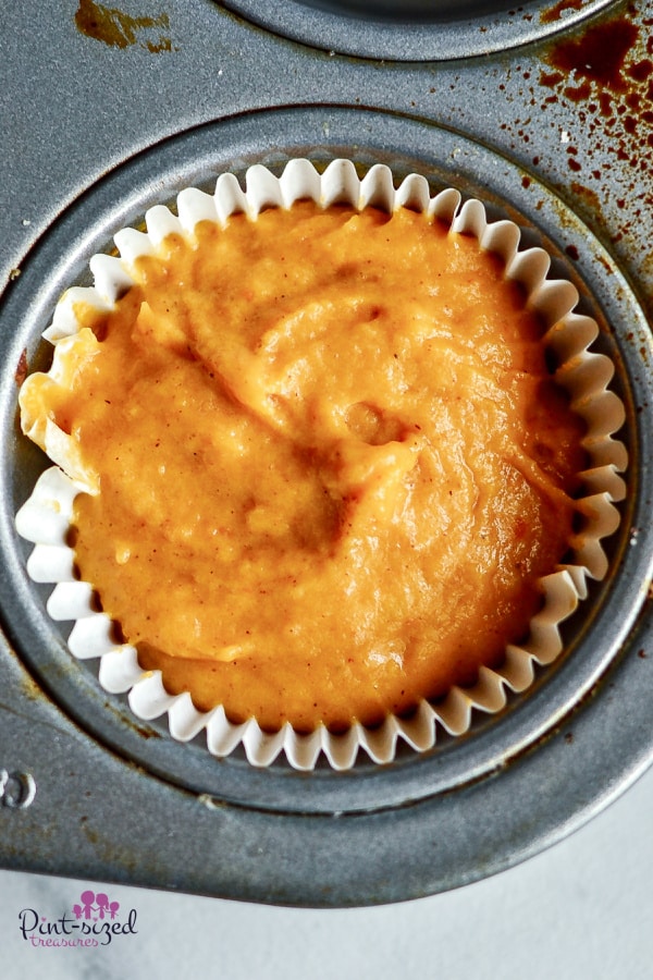 adding pumpkin muffin batter to muffin tins
