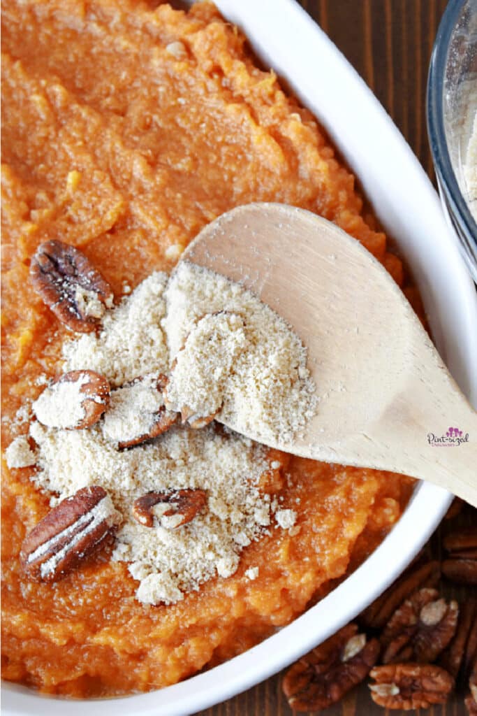 adding streusel pecan topping to sweet potato casserole