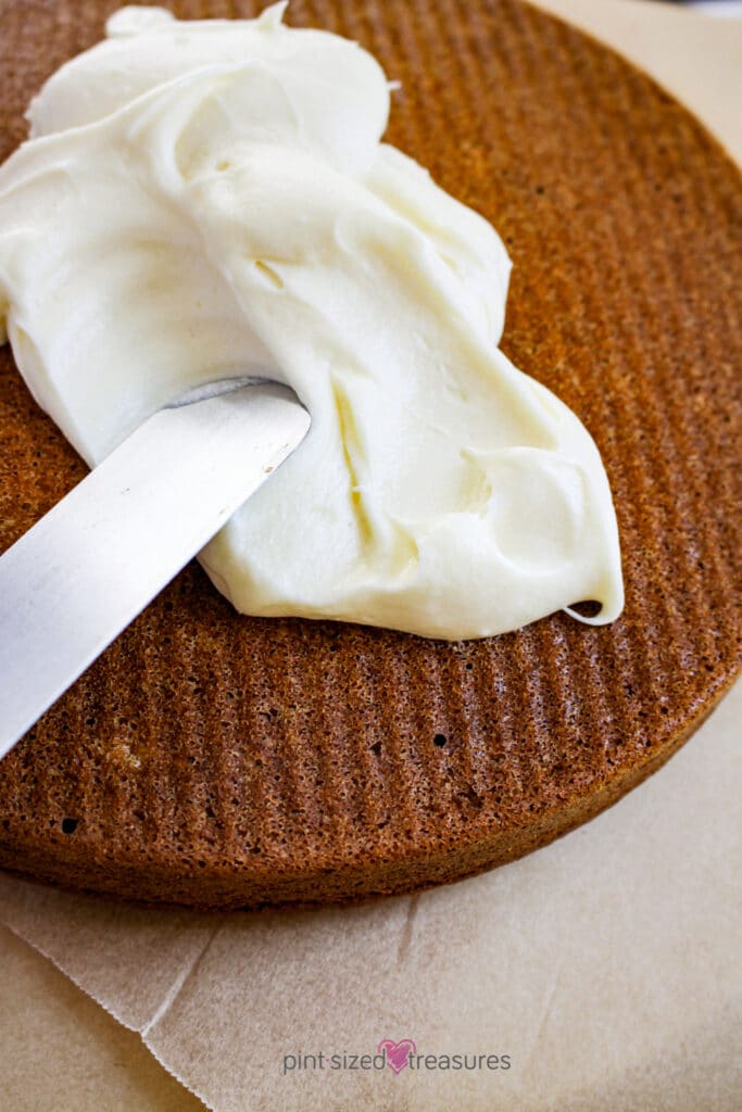 spreading homemade frosting on the classic sweet potato cake